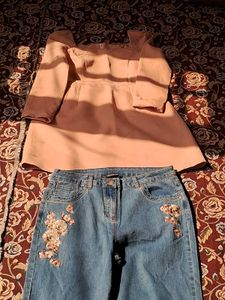 A long-sleeved pink top and embroidered blue jeans