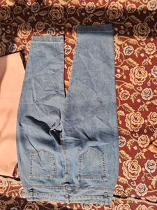A long-sleeved pink top and embroidered blue jeans