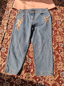 A long-sleeved pink top and embroidered blue jeans