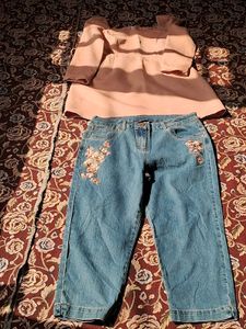 A long-sleeved pink top and embroidered blue jeans