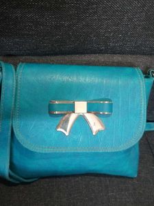 BLUE SLING BAG WITH ADJUSTABLE STRAP.
