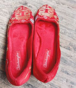 A pair of red, embroidered flat shoes..