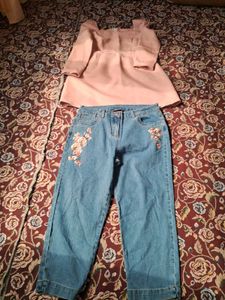 A long-sleeved pink top and embroidered blue jeans