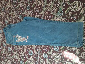 A long-sleeved pink top and embroidered blue jeans