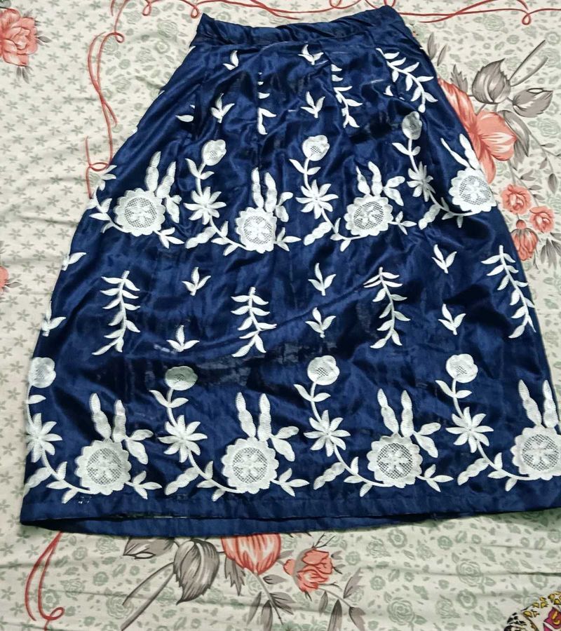 A navy blue ethenic skirt with shiny material .