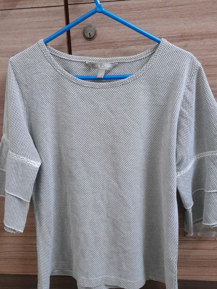 It&#39;s Black, White With a Slight Grey Shade In It. It Has a Circle Like Design, Very Comfy, Simple Yet Good Looking Top. It Is Stretchable. Pair It With A Black Jeans You Will Look Amazing.